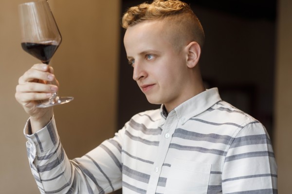 Young man examining glass of wine