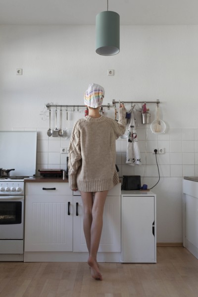 Rear view of young woman in apartment kitchen