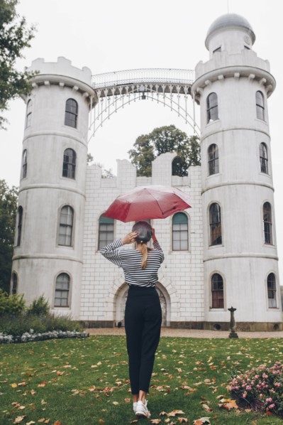 Woman holding red umbrella by Schloss Pfaueninsel in Potsdam, Germany