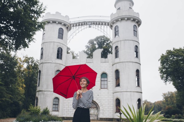 Woman holding red umbrella by Schloss Pfaueninsel in Potsdam, Germany