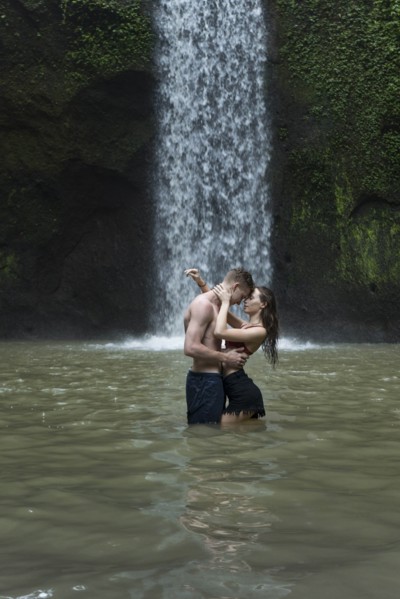 Young couple embracing in river by Tibumana Waterfall in Bali, Indonesia