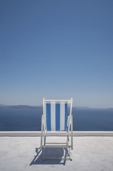 Striped deck chair on balcony by sea in Santorini, Greece