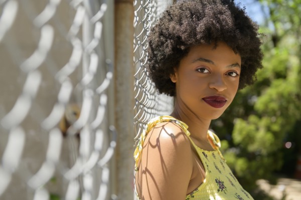 Portrait of young woman by wire fence