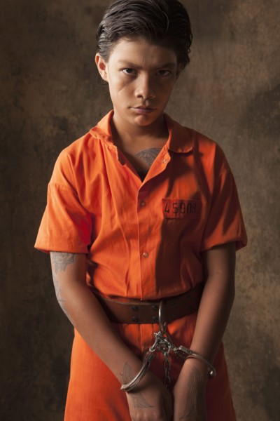 Boy in prisoner jumpsuit and handcuffs