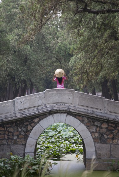 Woman wearing conical hat on arch bridge in Summer Palace gardens, Beijing, China