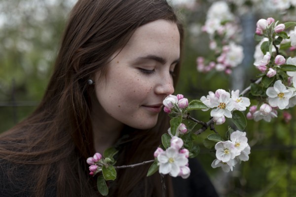 Young woman smelling white blossoms
