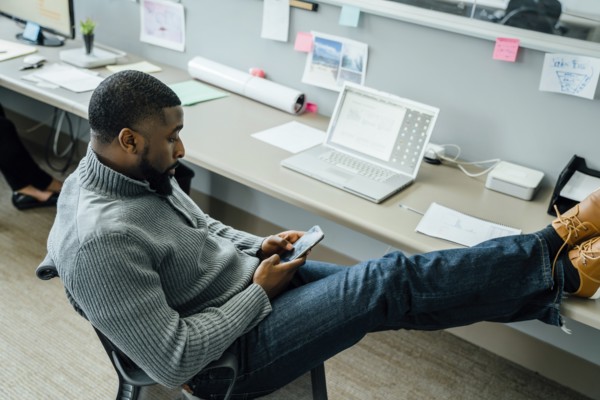 Man with his feet up using smart phone in office