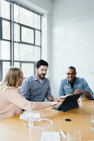 Coworkers using digital tablet in board room