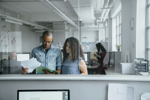 View through window of coworkers reading documents in office