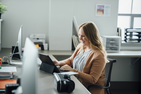 Smiling woman using digital tablet in office