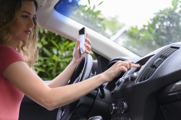 Young woman using smart phone and touchscreen in car