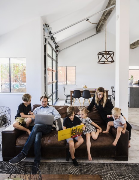 Family with book and laptop on sofa