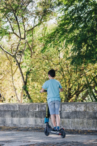 Boy using electric scooter on sidewalk