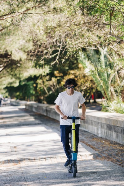 Young man using electric scooter on pavement