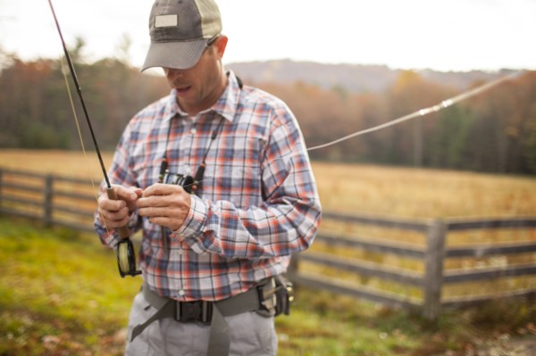 Man holding fishing rod by field