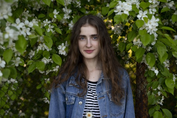 Young woman wearing denim jacket by white flowers