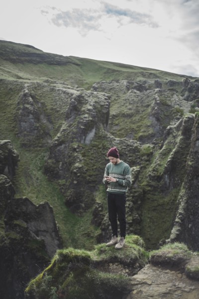 Man using smart phone on mountain in Kirkjubµjarklaustur