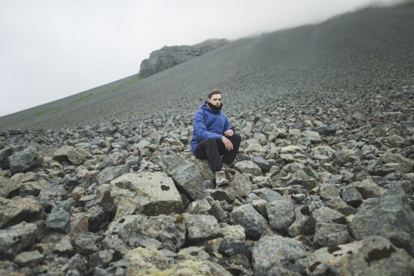 Young man sitting on rock hill in Kirkjubµjarklaustur