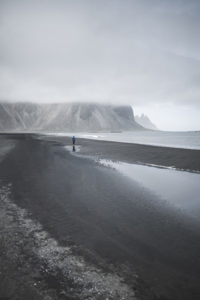 Man walking on black sand beach in Kirkjubµjarklaustur