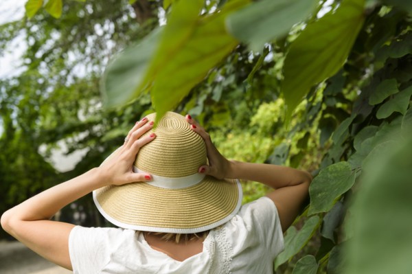Woman wearing straw hat by trees