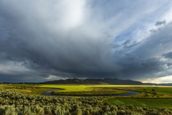 Cloudscape over river through fields in Picabo, Idaho, USA