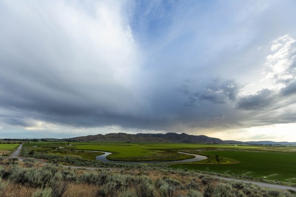 Cloudscape over river through fields in Picabo, Idaho, USA