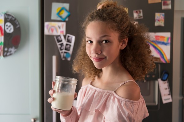 Girl holding glass of milk in kitchen