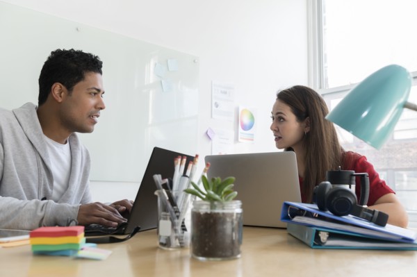 Coworkers using laptops in office