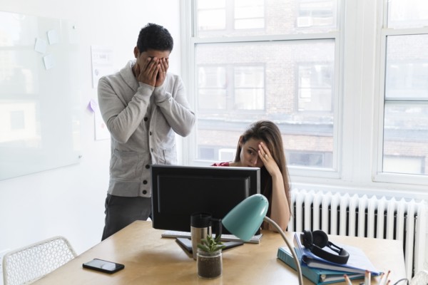 Stressed coworkers at computer together