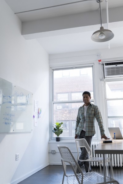 Businessman leaning on desk by whiteboard