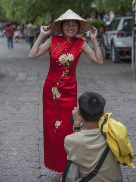 Man photographing woman wearing red dress in Lijang, Shangri-La Region, Yunnan Province, China