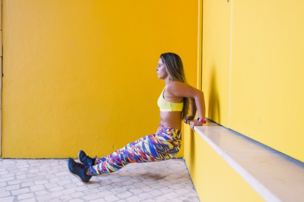 Woman doing wall sit by yellow wall