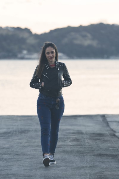 Woman walking on footpath by sea in Lisbon, Portugal