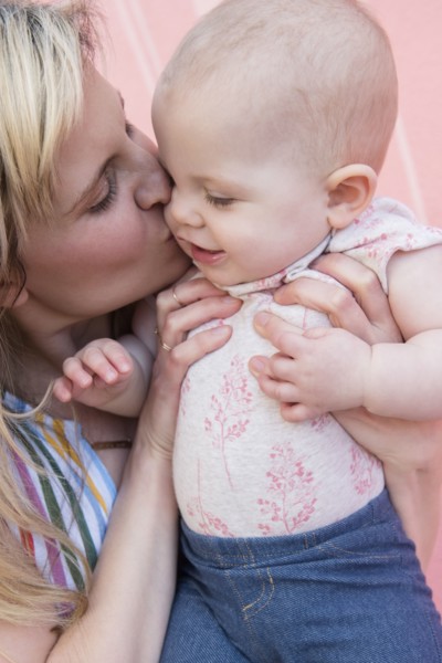 Baby girl being kissed by her mother