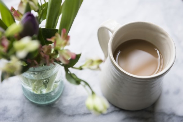 Cup of coffee beside flowers in vase