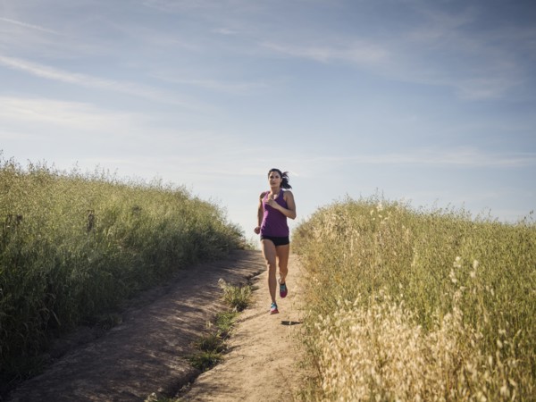Mid adult woman jogging on path through field