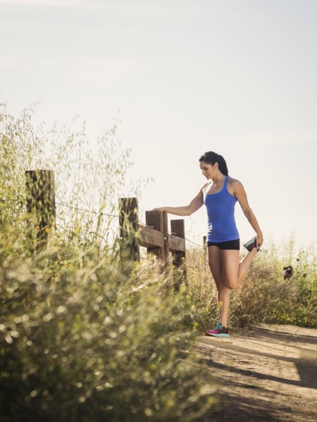 Woman in sportswear stretching on fence