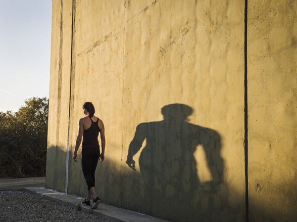 Woman in sportswear walking by concrete wall