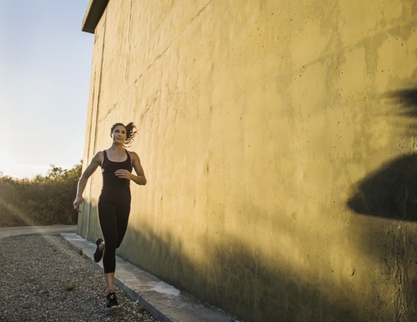 Woman in sportswear jogging by concrete wall
