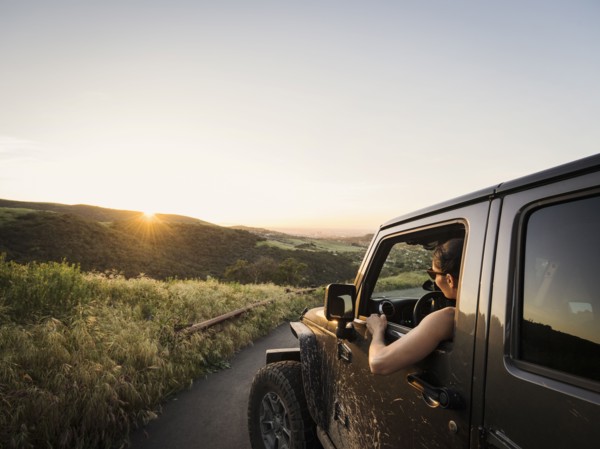 Woman in off road vehicle looking at sunset