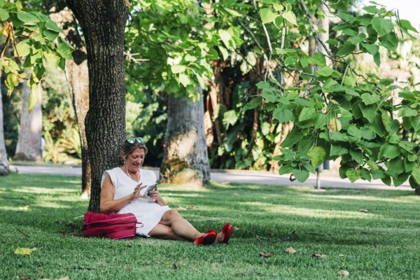 Woman using smart phone under tree