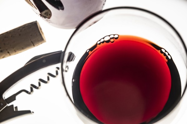 Glass of red wine with corkscrew and cork