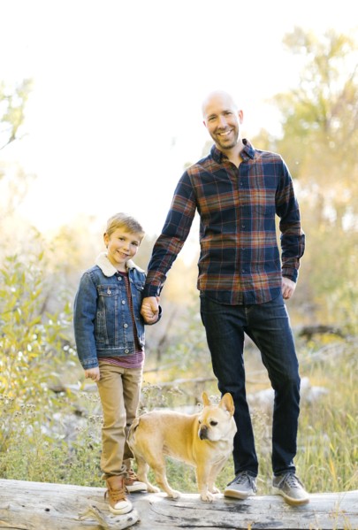 Father and son with pet French bulldog on fallen tree
