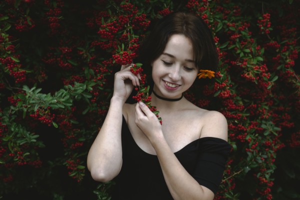 young woman standing by bush with red berries