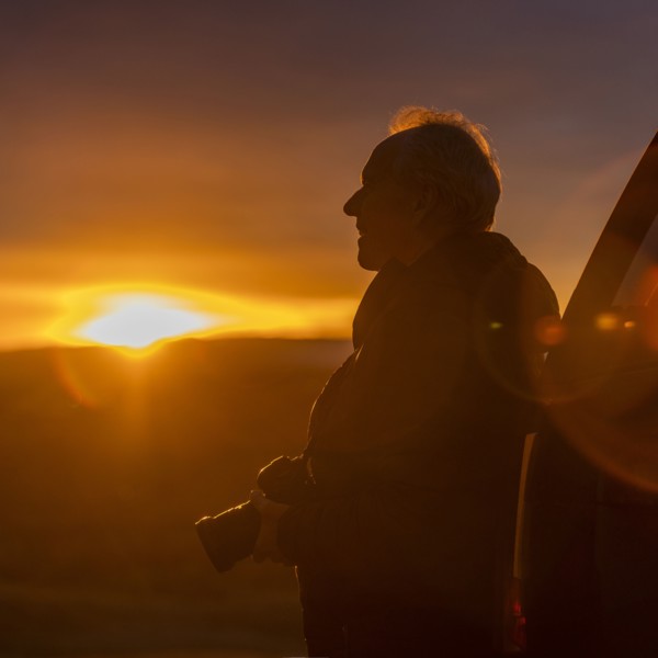 Senior man with camera at sunset