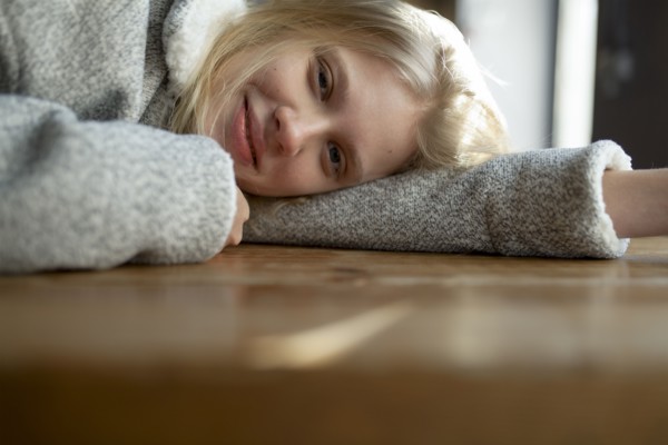 young woman in wool coat lying on cafe table
