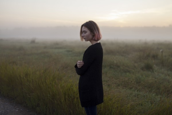young woman in field at sunset
