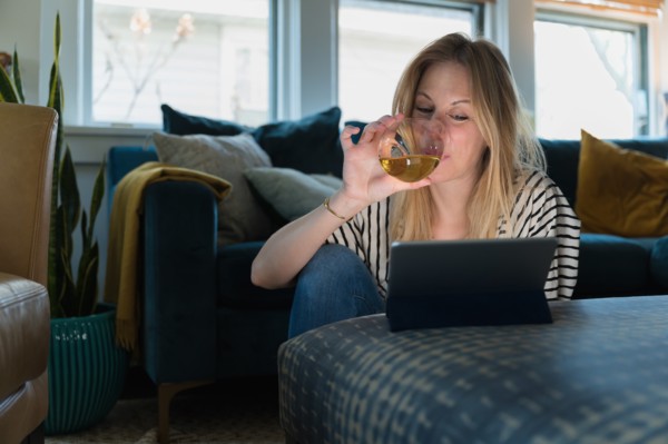 Woman drinking wine and looking at tablet at home