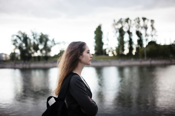 Woman walking near lake in cloudy weather
