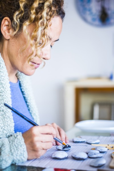 Woman painting stones at home